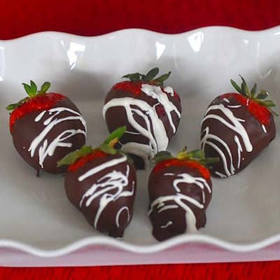 Chocolate covered strawberries with white chocolate drizzled on it.